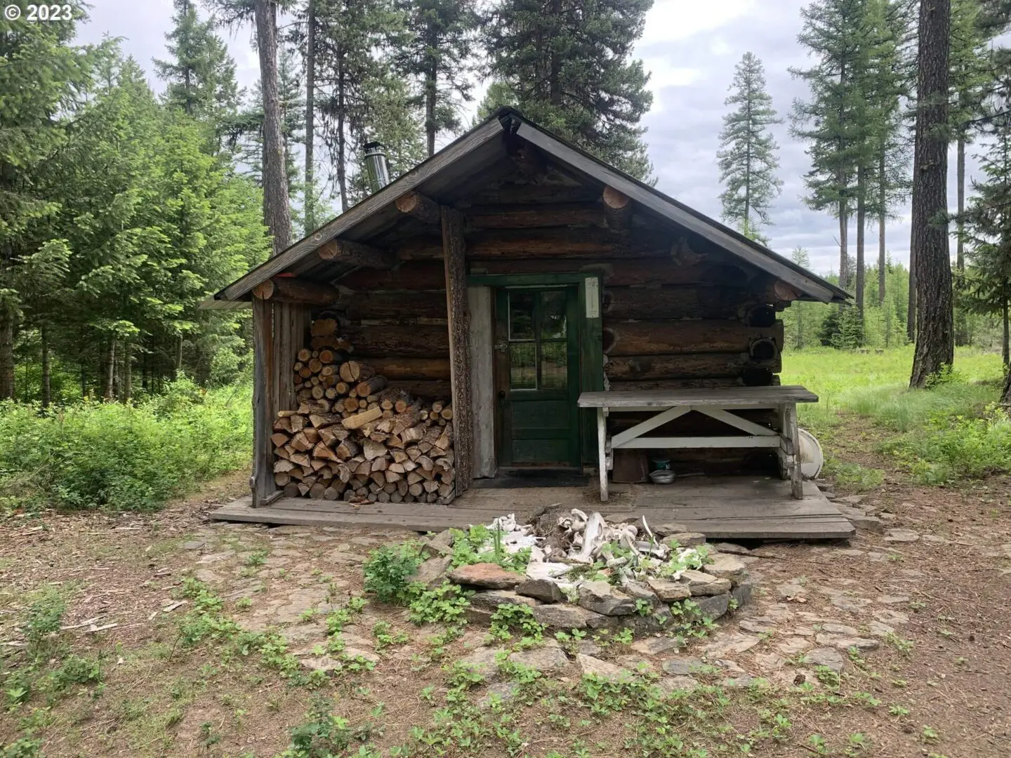 A log cabin with wood stacked on top of it.