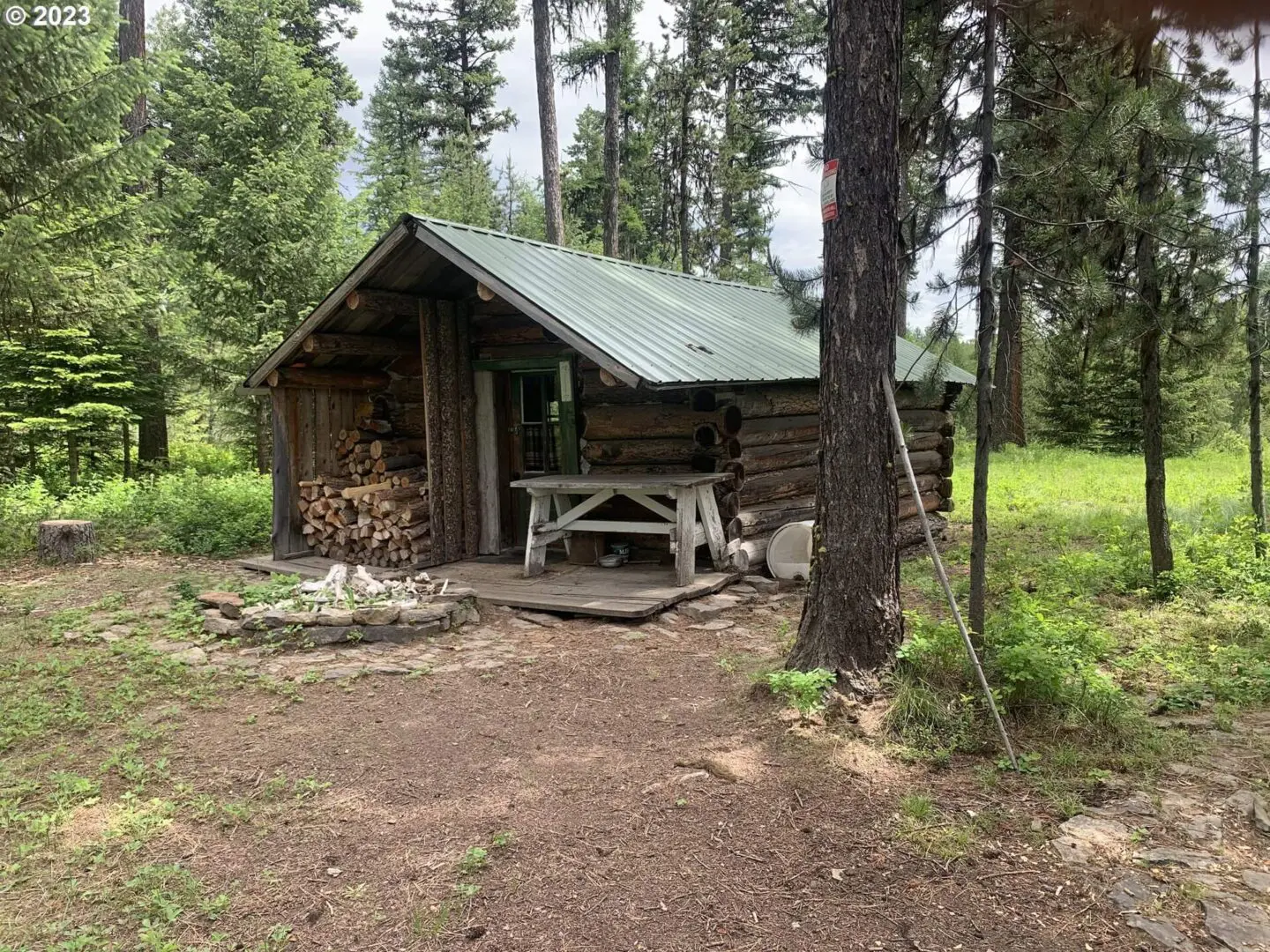 A cabin in the woods with a picnic table.