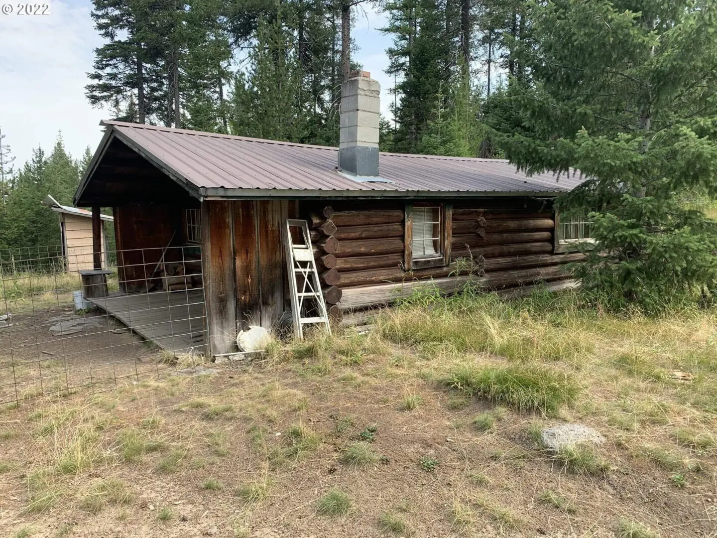 A log cabin with a ladder in front of it.