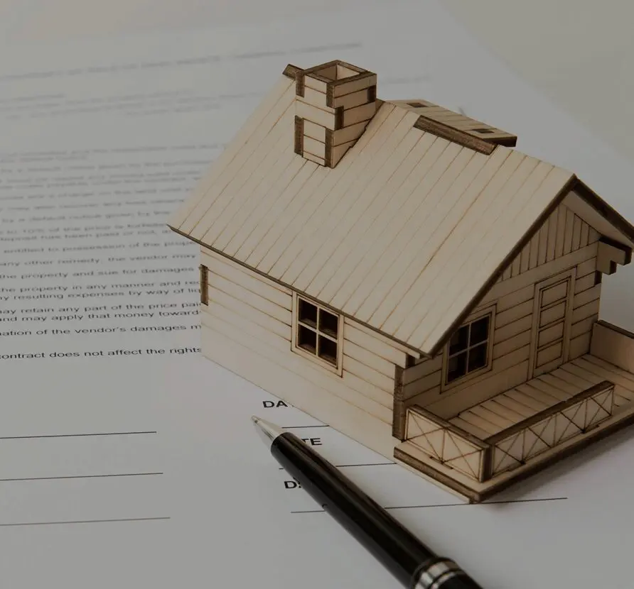 A pen and some paper with a wooden house on top of it