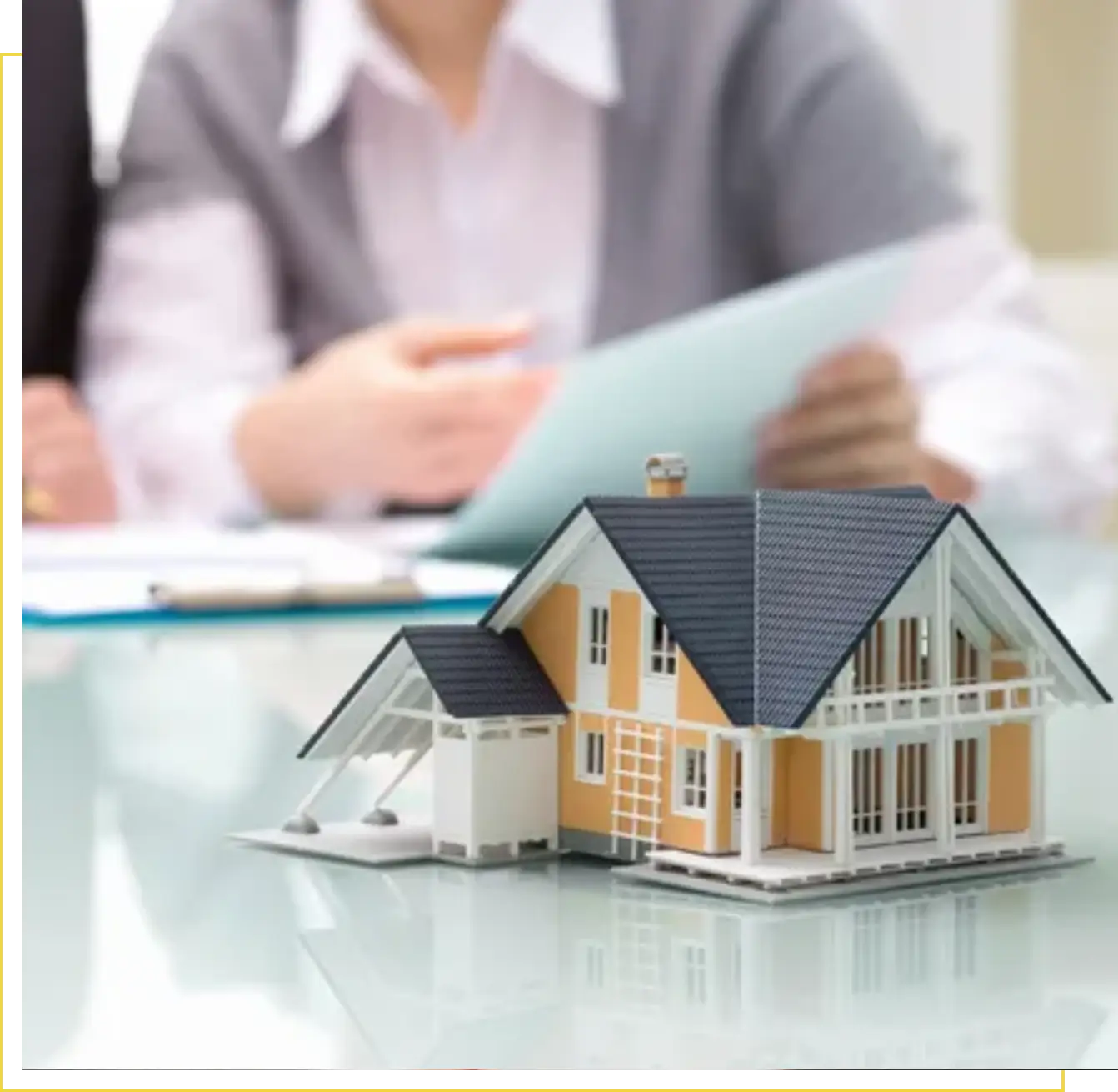 A person sitting at a table with a model house.