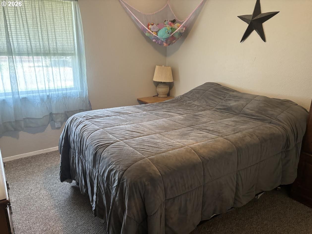Cozy bedroom with gray bedding and window.