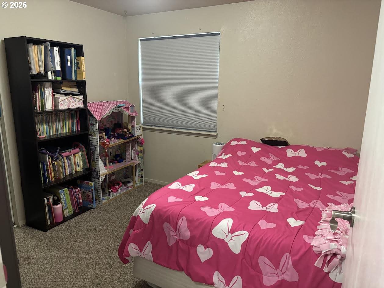 Cozy bedroom with pink bedding and bookshelf.