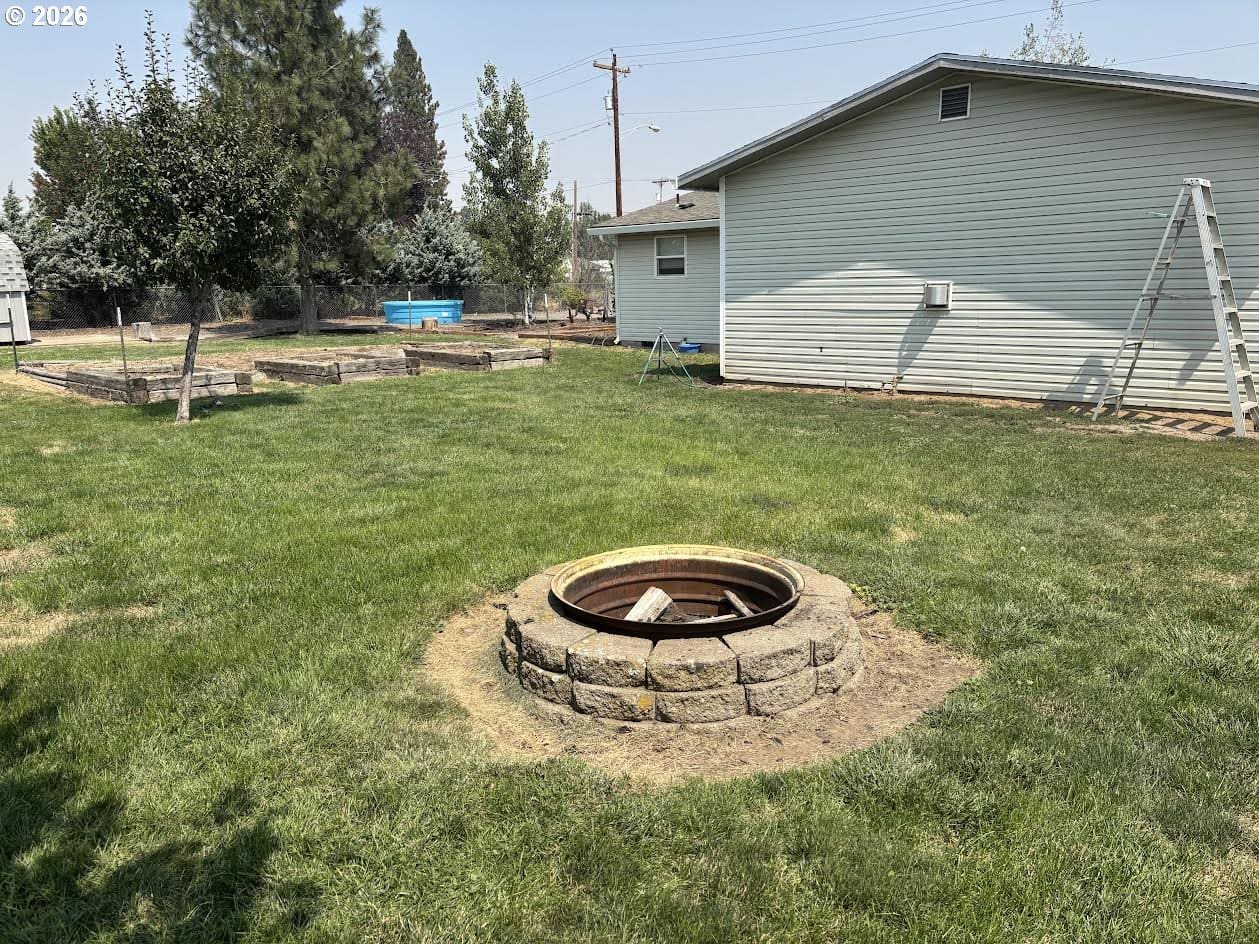 Backyard with fire pit and grassy area.