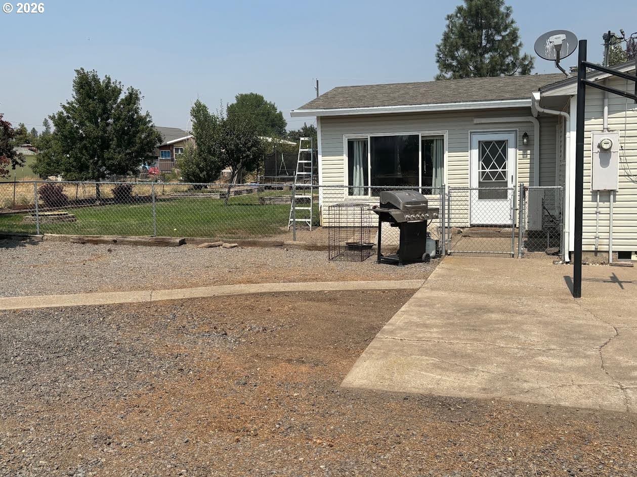 Backyard view with grill and fenced area.