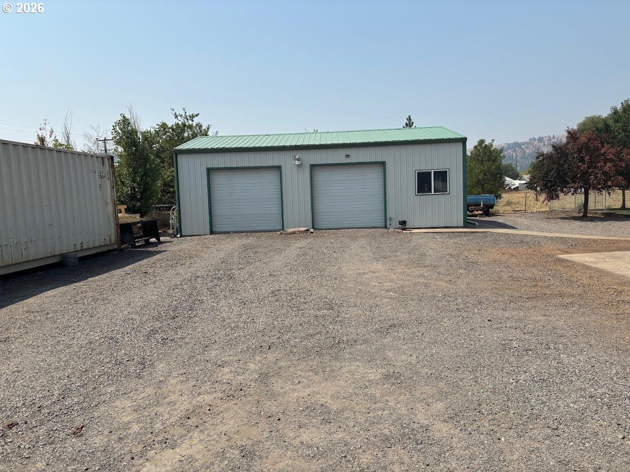 Metal storage building with gravel driveway.