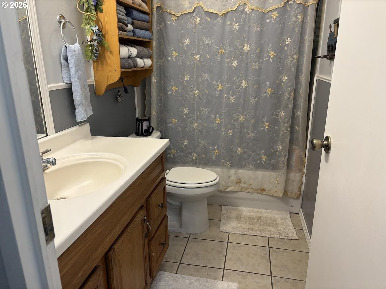 Small bathroom with towels and floral shower curtain.