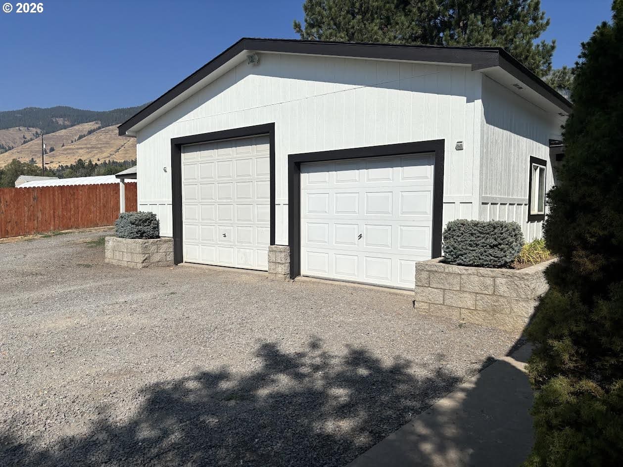White garage with two doors and landscaping.