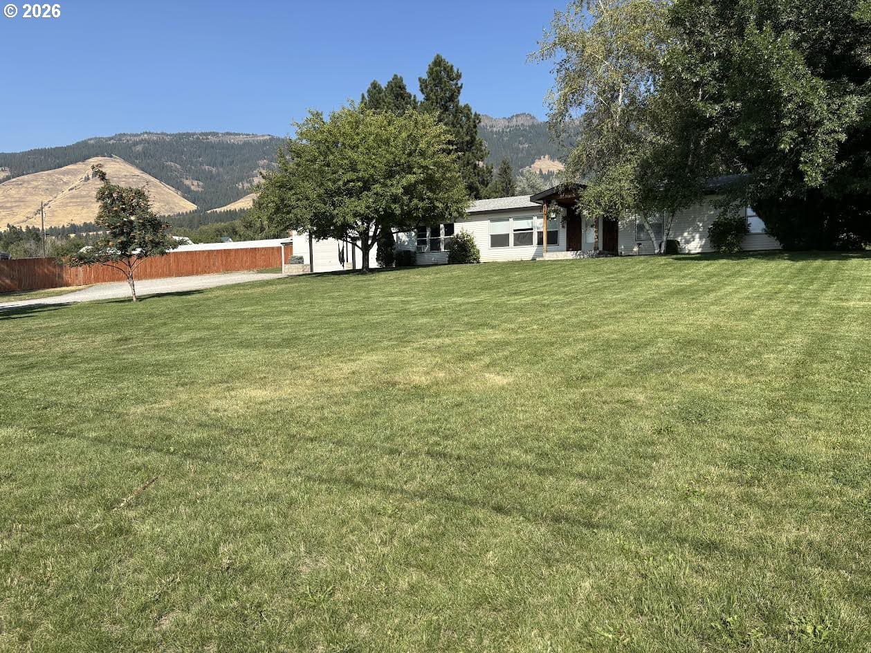 Single-story house with expansive green lawn.