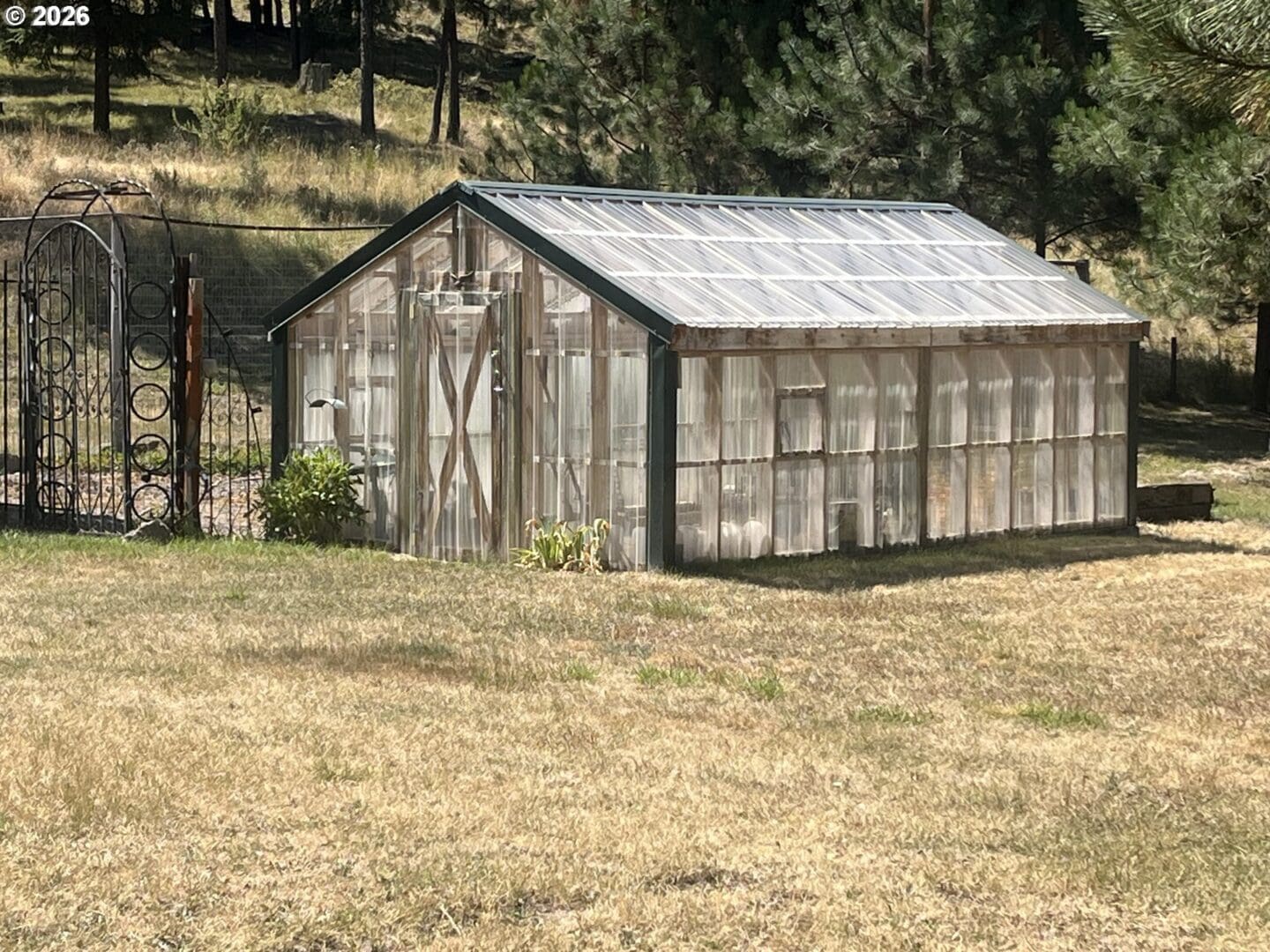 Greenhouse adjacent to a decorative gate.