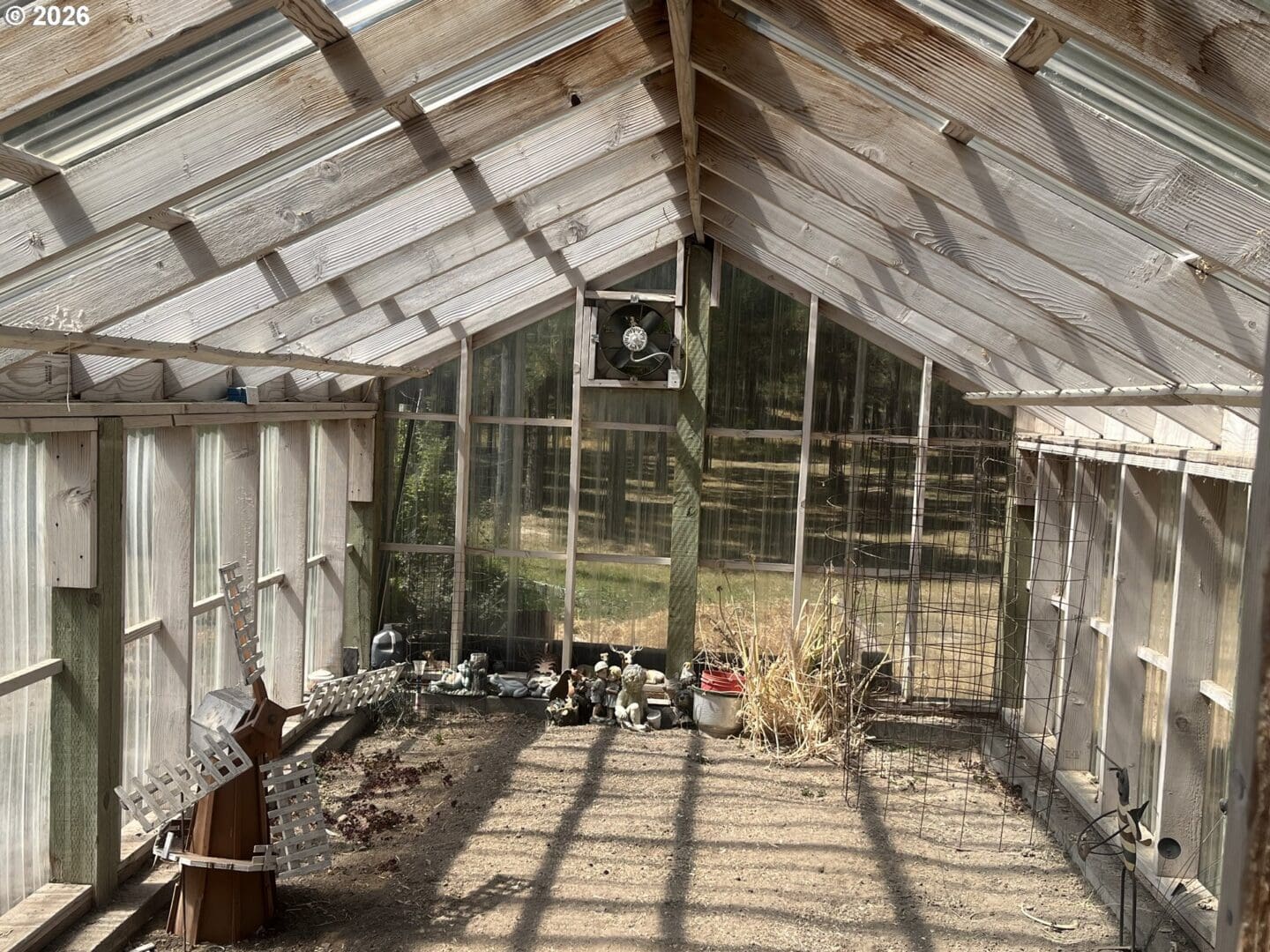 Empty greenhouse with wooden structure and sunlight.