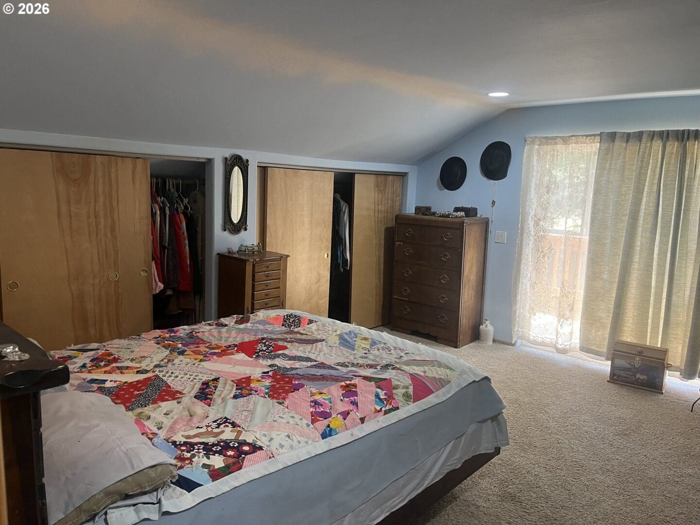 Cozy bedroom with quilt and wooden furniture.