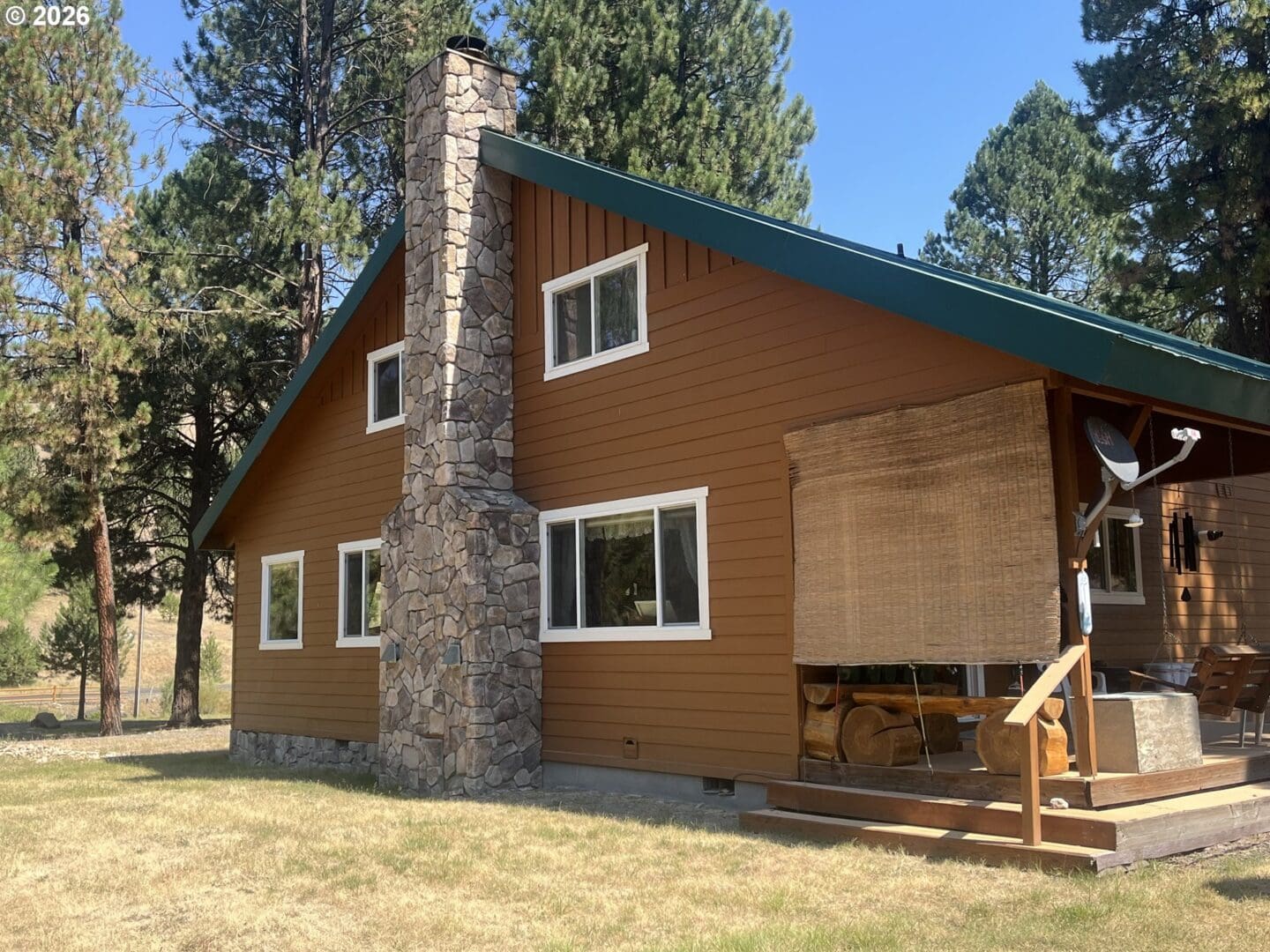 Brown house with stone chimney and porch.