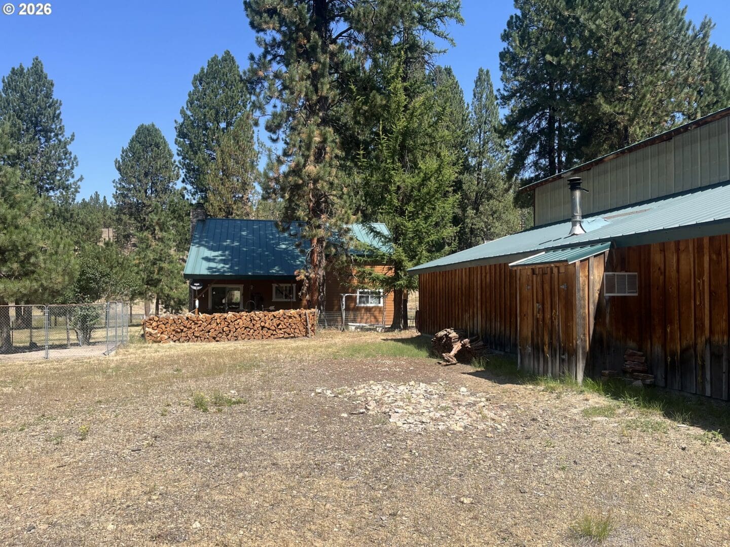 Rustic cabin with green roof and trees.